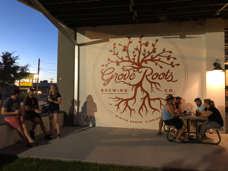 Families and couples sitting outside of Grove Roots on the patio with the mural in sight
